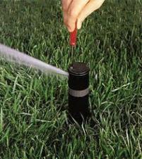 a tech adjusts the spray pattern of a sprinkler head with a screwdriver